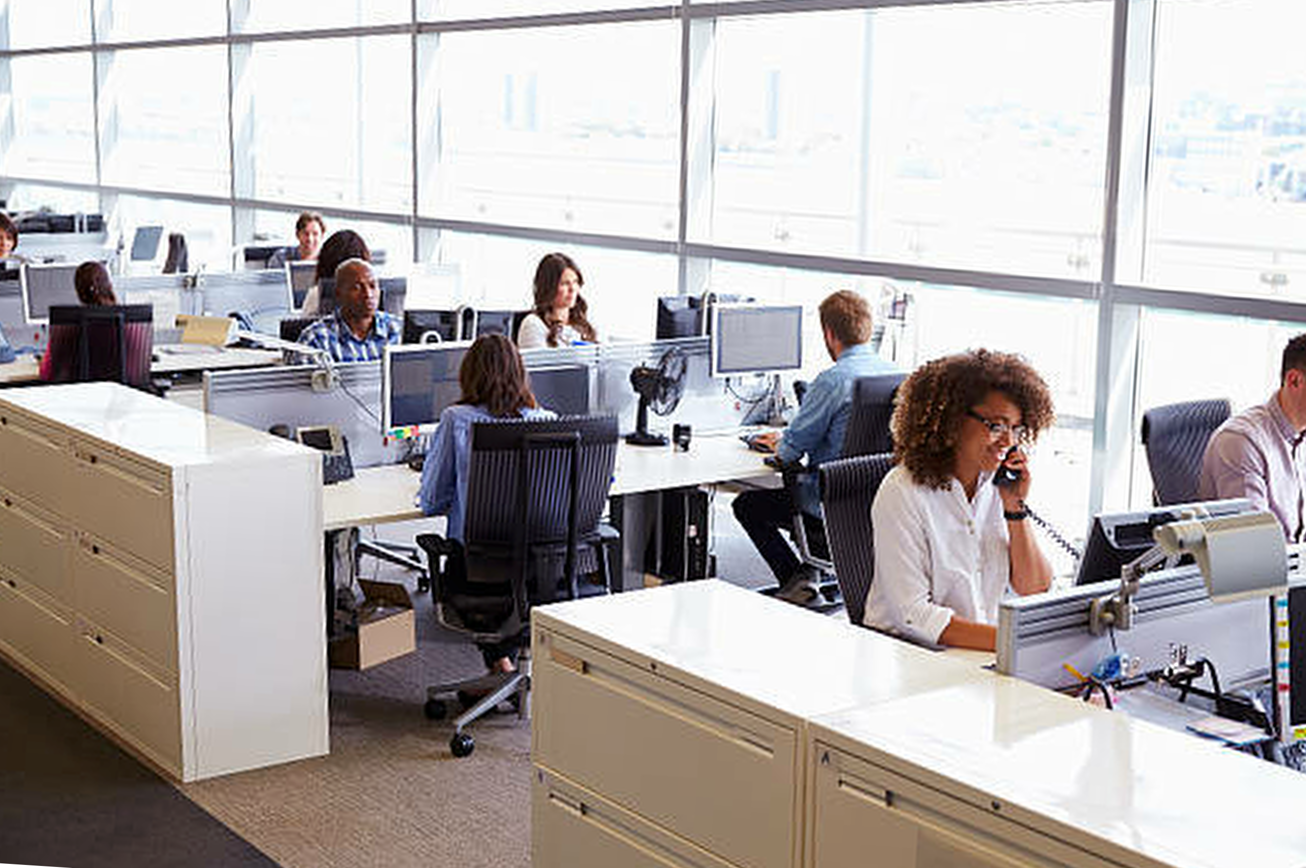 An office is filled with multiple workers at their desk.