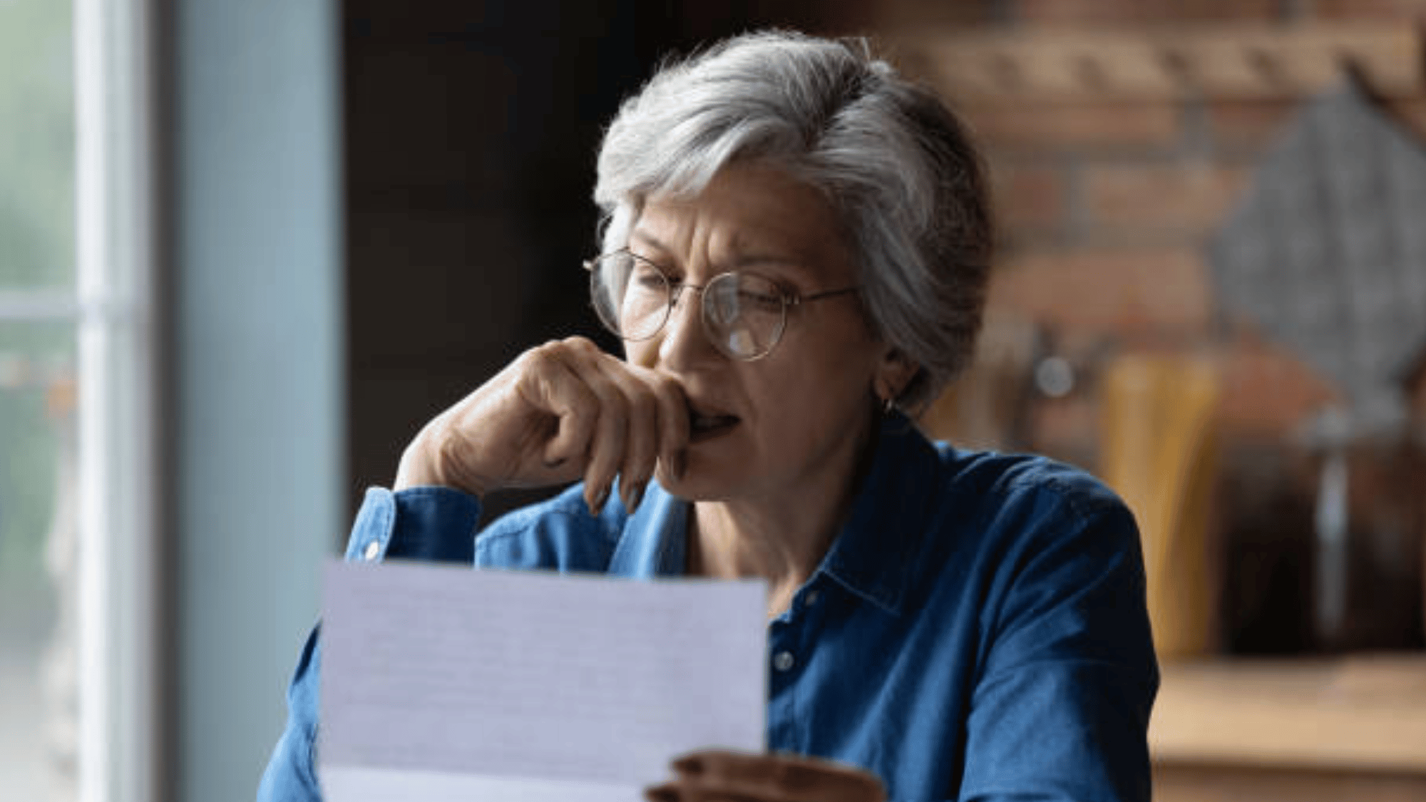 An older woman looks at a piece of mail.